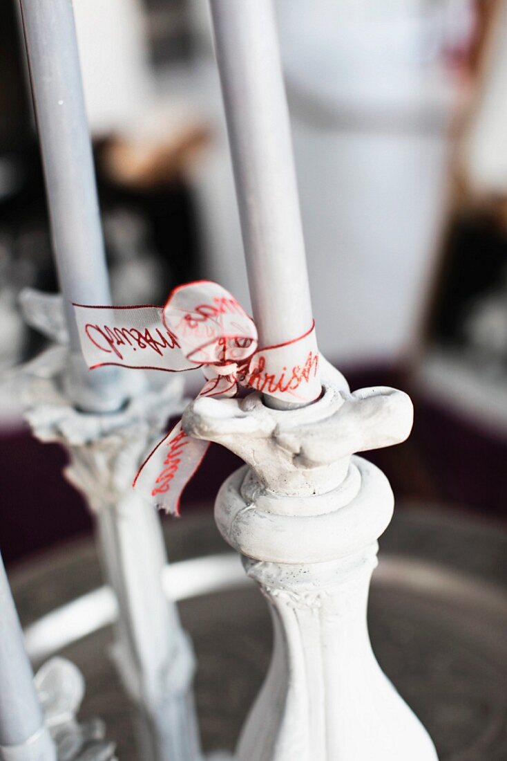 Ribbons with lettering tied around white candles as Advent arrangement