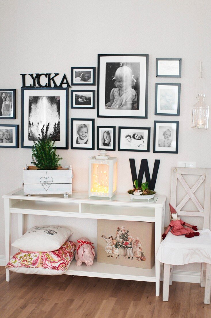 White console table below black and white photos in black frames on wall