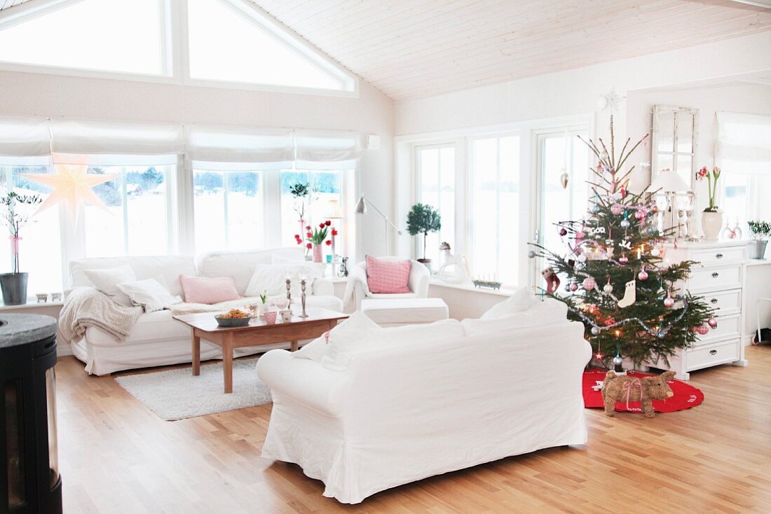 weiße Sofagarnitur und geschmückter Weihnachtsbaum in offenem Wohnbereich mit ländlichem Flair