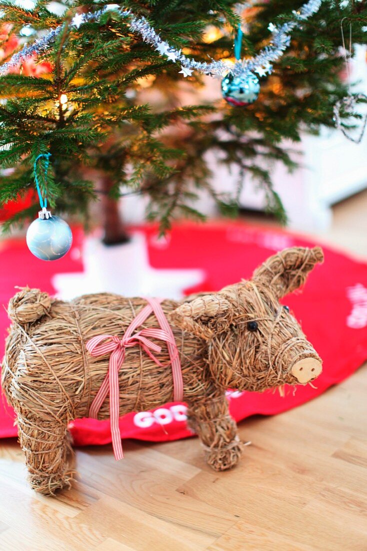 Straw pig in front of partially visible Christmas tree