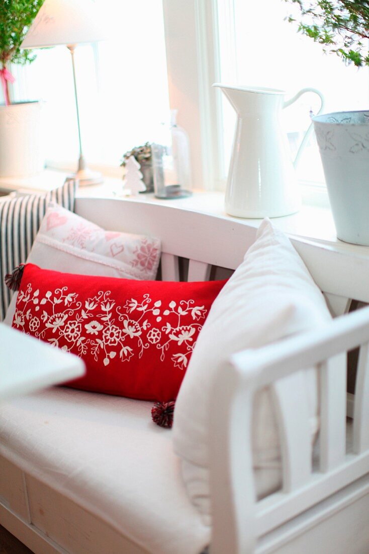 Red and white cushions on rustic wooden bench below window