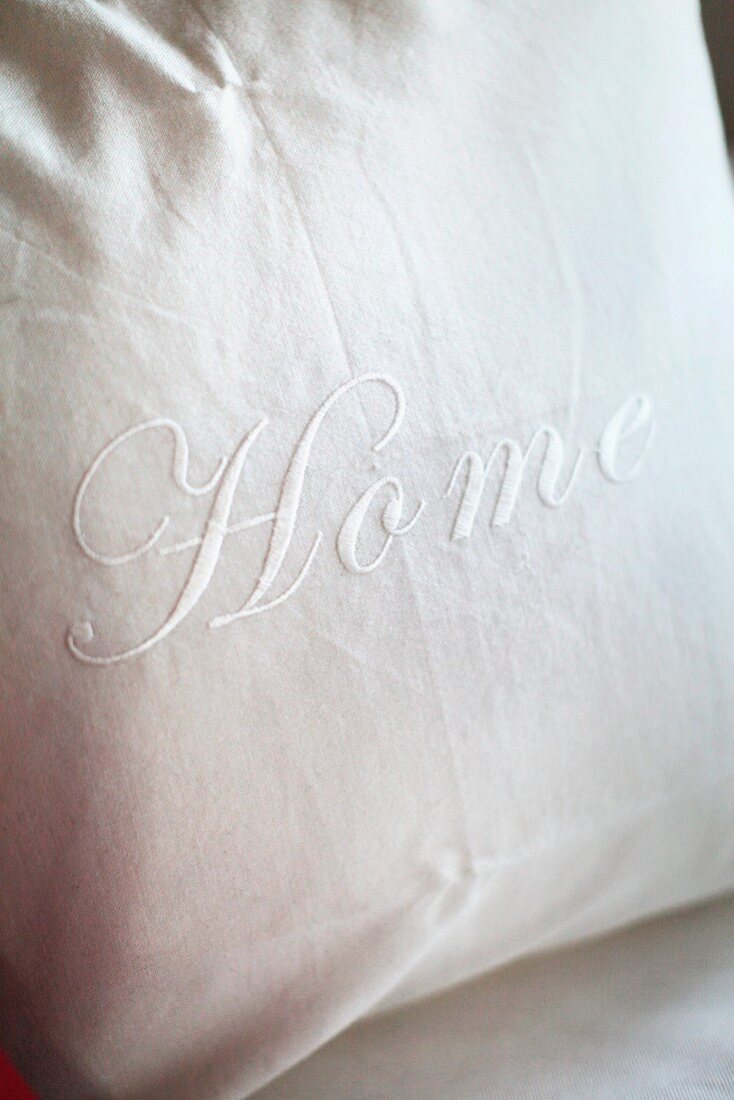 White cushion cover embroidered with lettering
