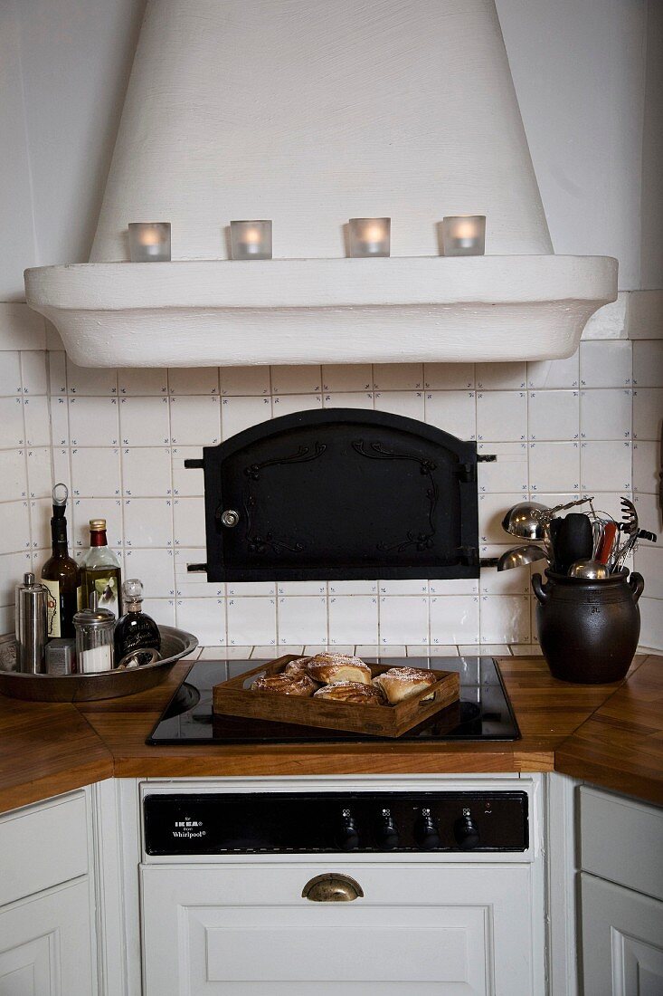 Country-house-style fitted kitchen with masonry extractor hood above ceramic hob