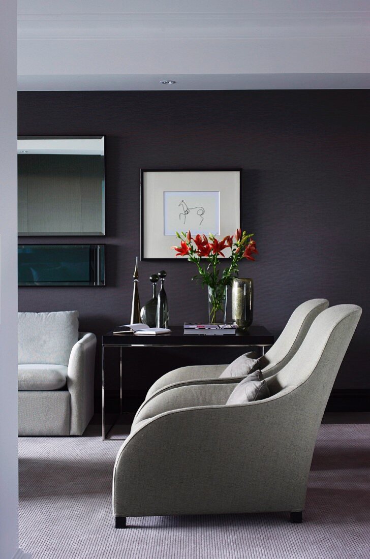 Extravagante Sessel mit graufarbenem Bezug in elegantem Wohnzimmer mit dunkel getönter Wand