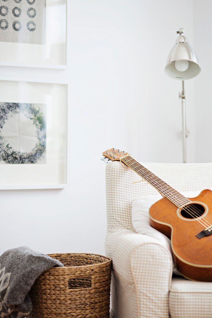 Gitarre auf teilweise sichtbarem Sessel vor Retro Stehleuchte in Zimmerecke