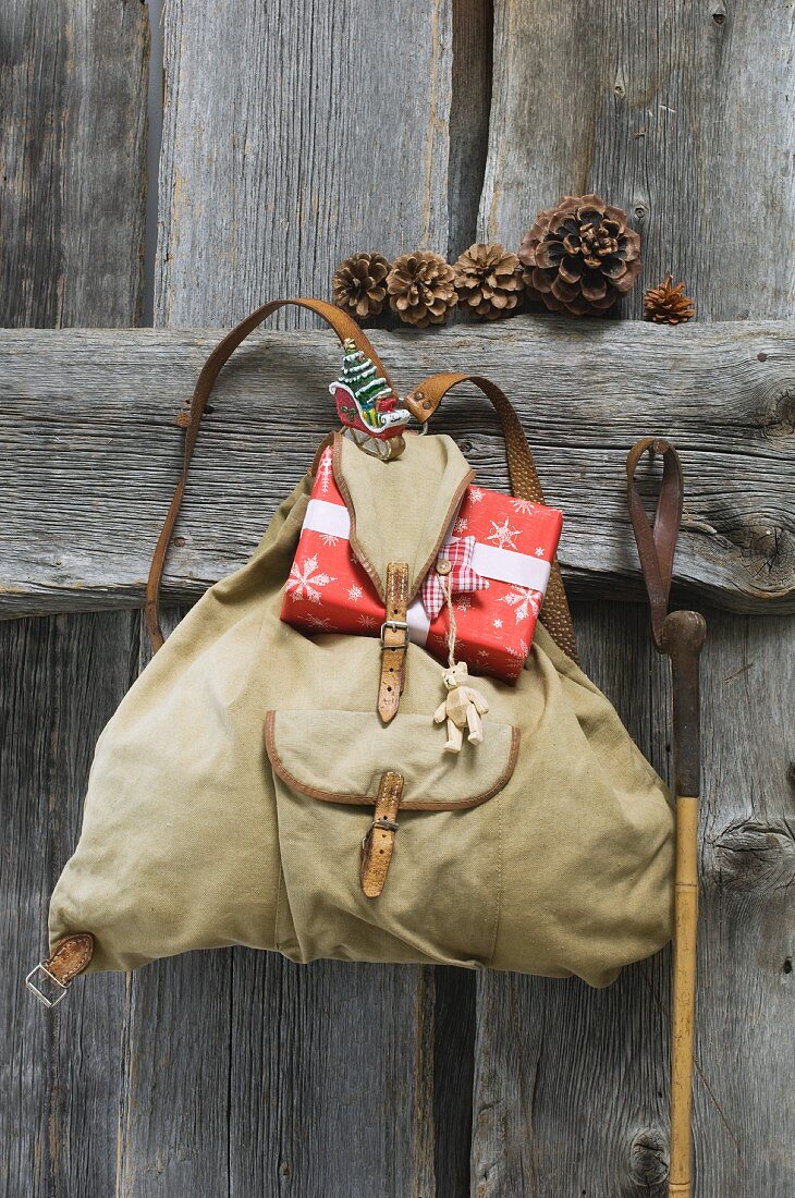 Tradtioneller Rucksack mit darin steckendem Weihnachtsgeschenk; daneben ein alter Skistock