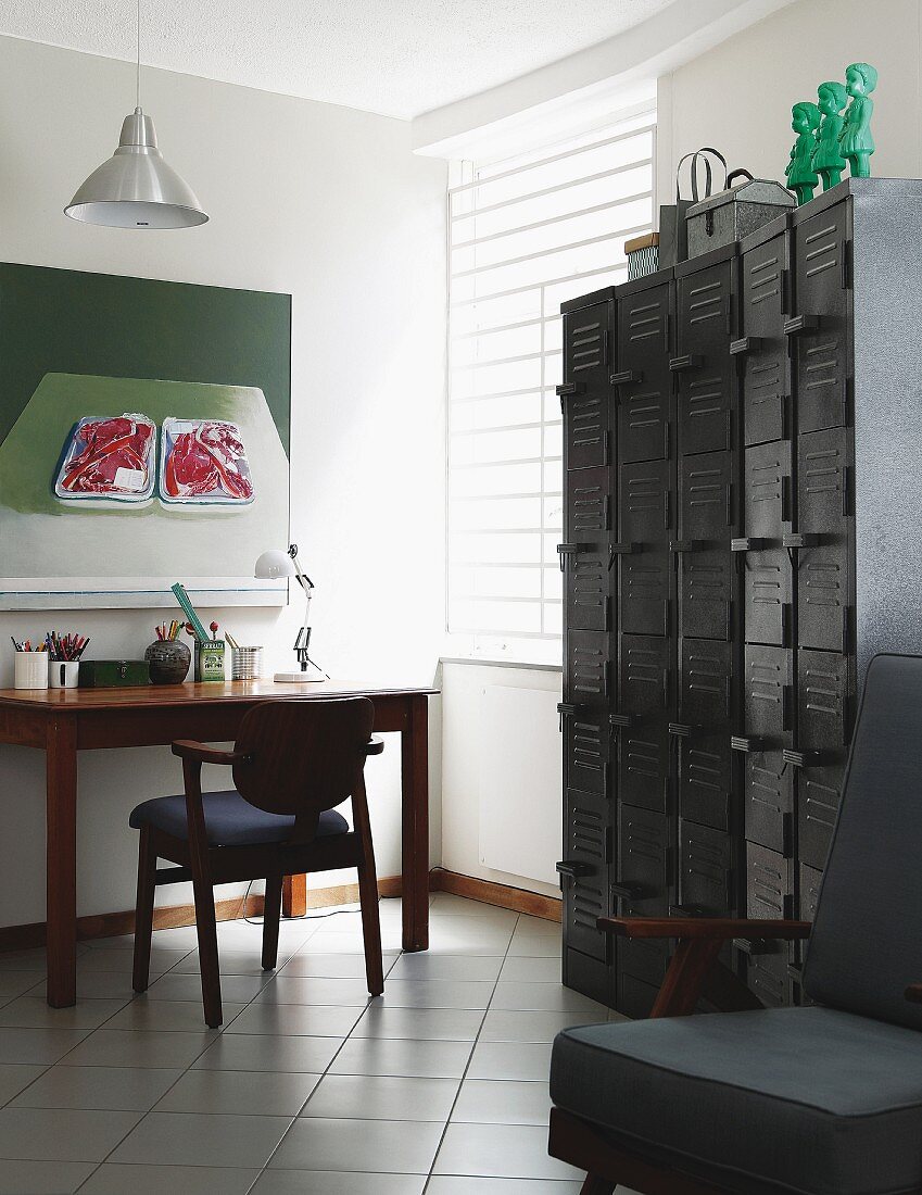 Retro Schliessfachschränke aus Metall, gegenüber Arbeitsplatz mit gepolstertem Stuhl und Holztisch, vor Wand mit modernem Bild