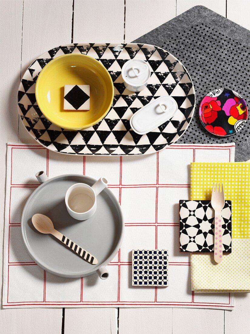 Crockery on grey tray and patterned tray on various table mats