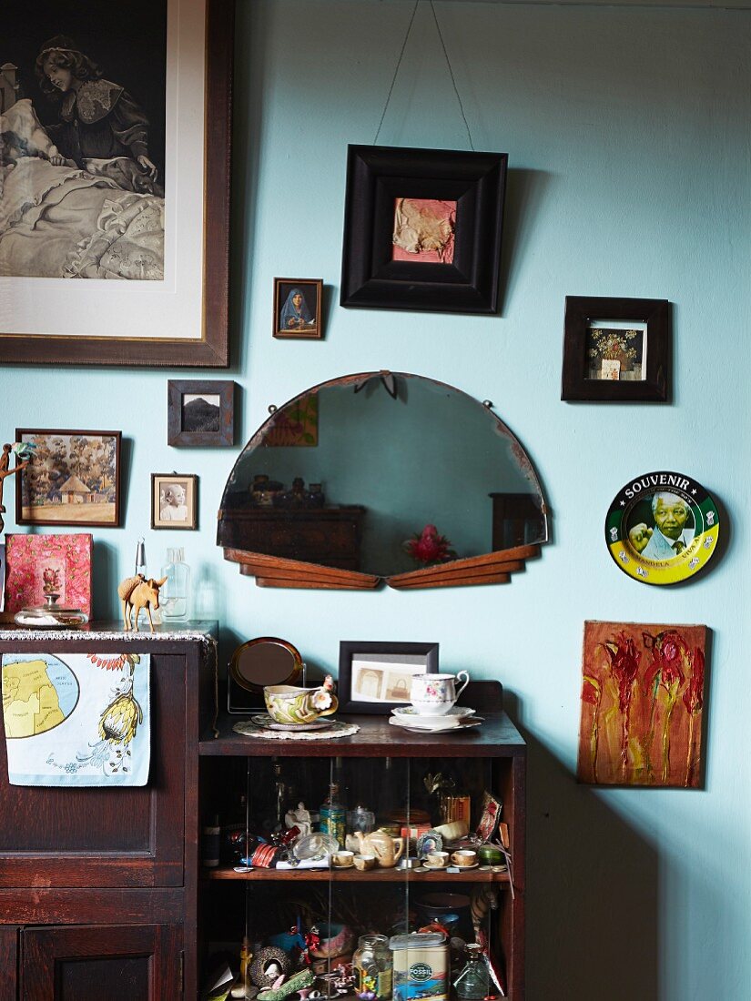 Open-fronted, dark wood, vintage-style shelving below pictured and semicircular mirror on painted wall