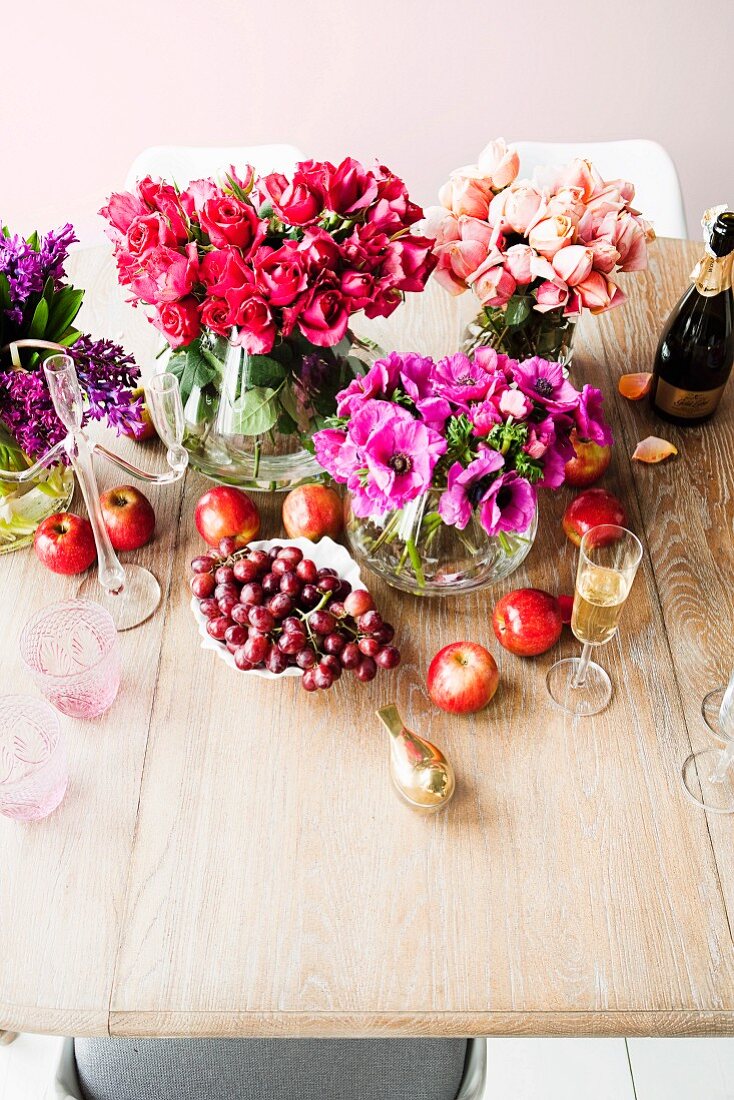 Blumensträusse in Vasen und Obst auf schlichtem Holztisch