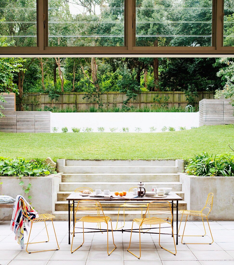 Terrassenplatz mit Frühstückstisch eines Architektenhauses mit modernem Gartenpool im Hintergrund