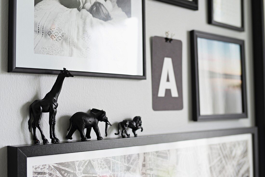 Bildergalerie mit winzigen, schwarzen Tierfiguren auf einem Rahmen