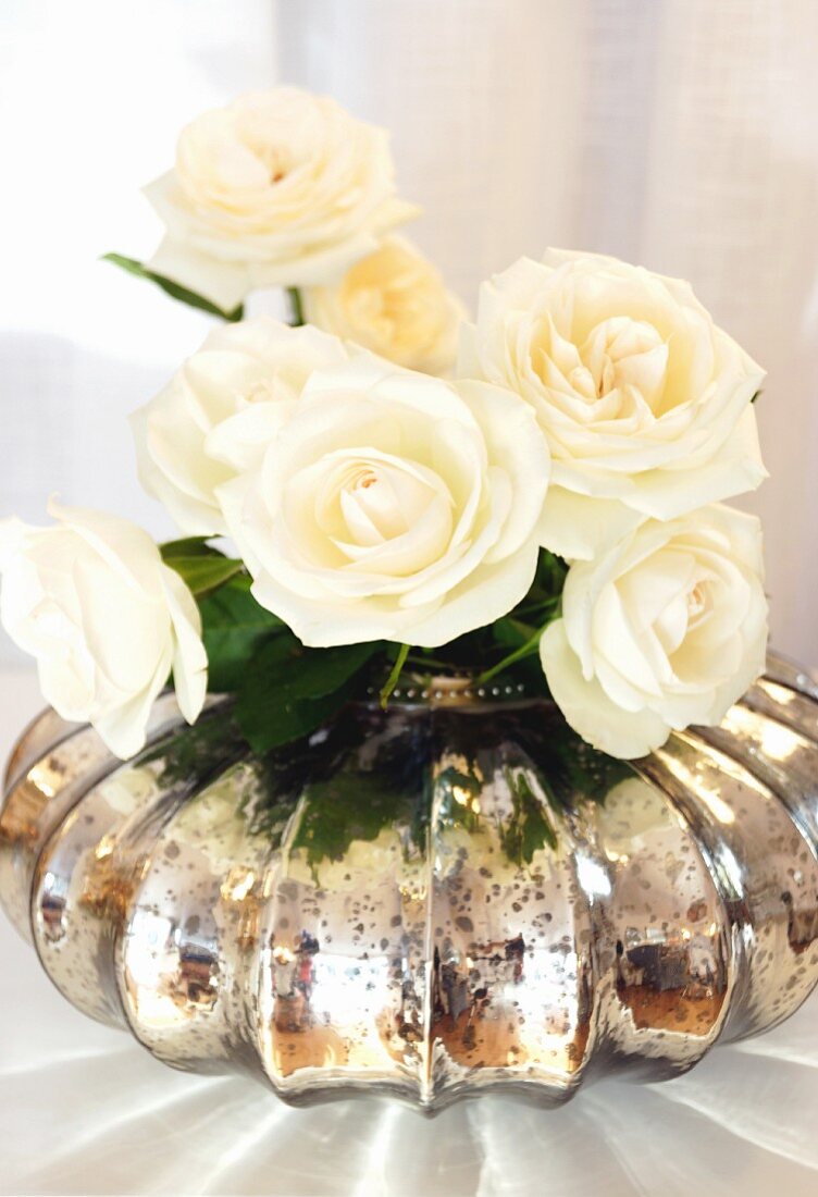 White roses in mercury glass vase