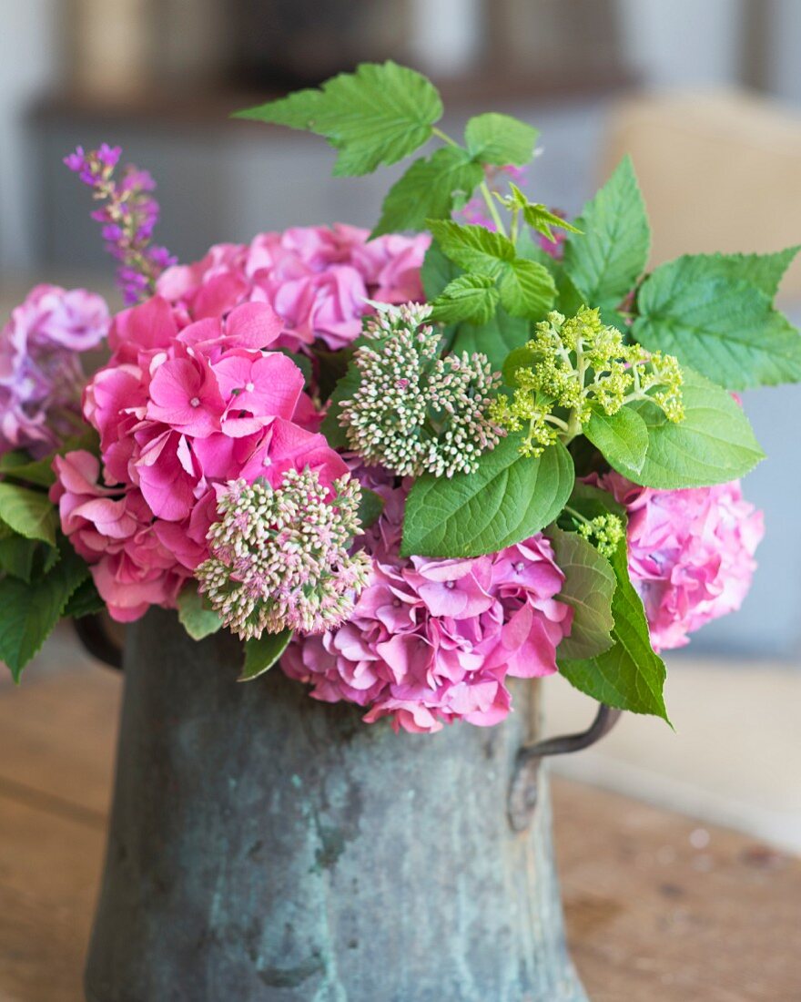 Summery bouquet of garden flowers with pink hydrangeas in vintage metal jug