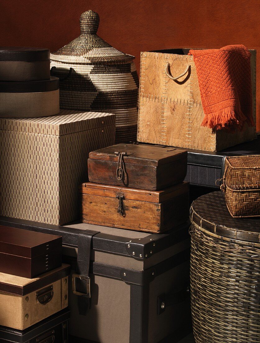 Gestapelte Aufbewahrungsbehälter aus verschiedenen Materialien wie Korb, Holz, Pappe, Leder auf engstem Raum