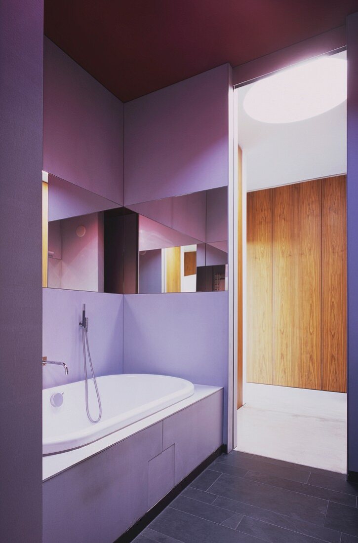 Violett schimmernde Wand in modernem Bad mit Spiegelband über der eingebauten Wanne