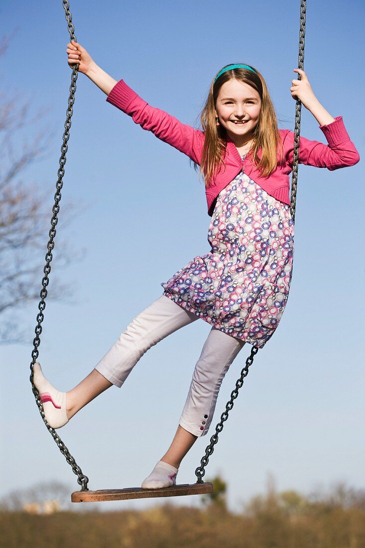 A girl standing on a swing