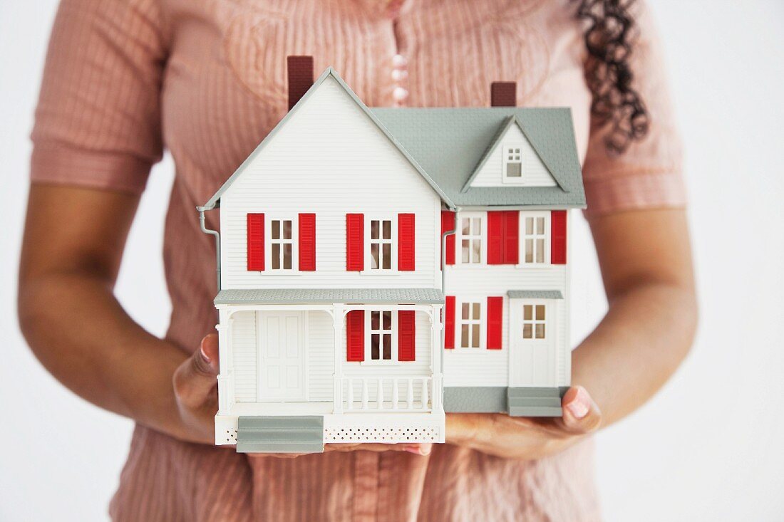 Midsection of a woman holding a miniature house