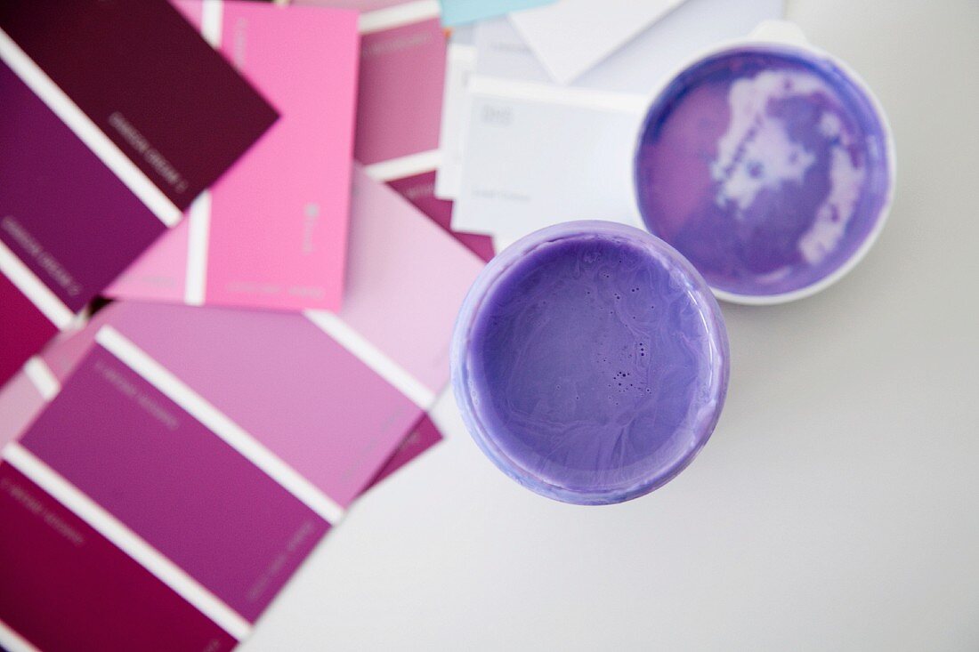 Offener Farbdosen mit violetter Farbe neben Farbkarten