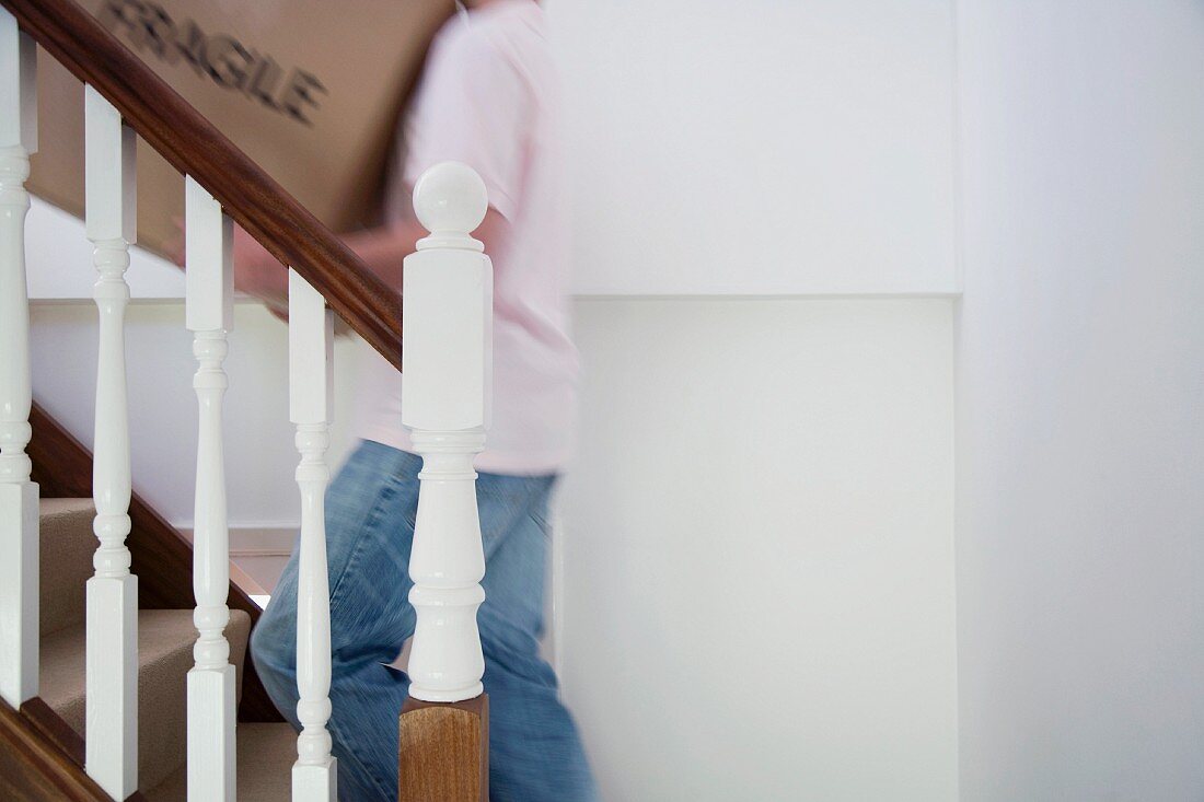 Mann trägt Kiste auf der Treppe
