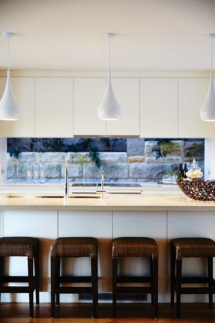 Moderne Küche in Weiß mit Hängelampen und braunen Hockern