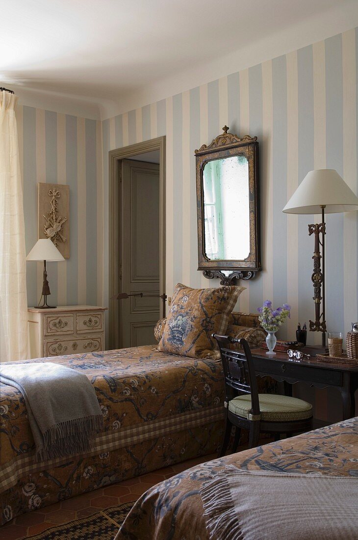 Charming guest room with antique, country-house furniture and striped, pastel wallpaper