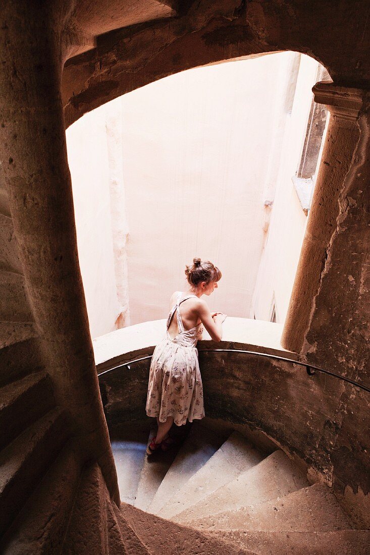 A woman leaning on a staircase balustrade and looking out