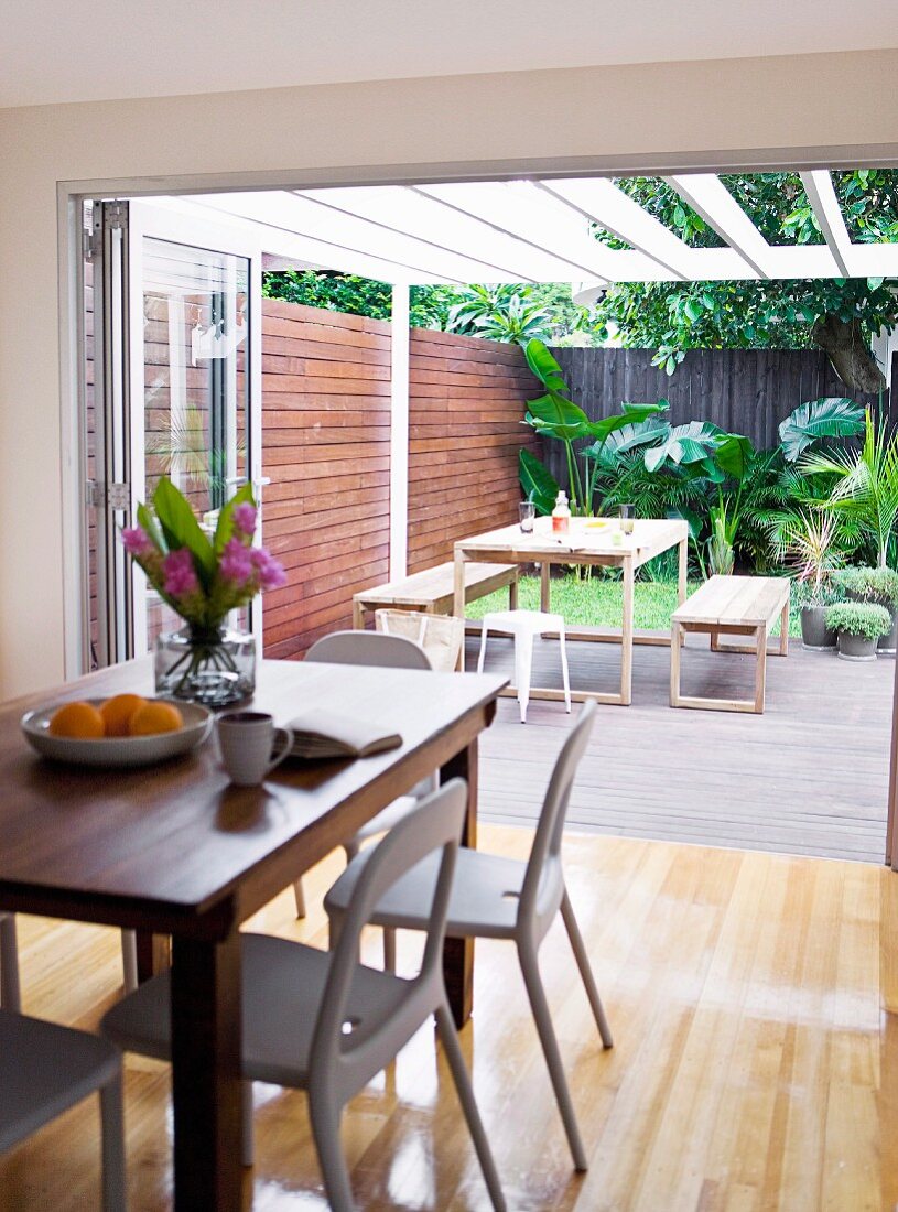 Modern dining area in front of open folding doors leading to terrace