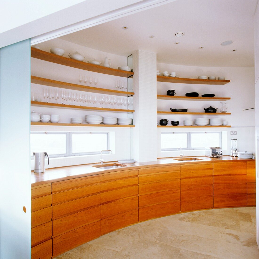 Küchenunterschränke aus Kirschbaum und Regale an runder Wand einer Penthouse-Wohnung