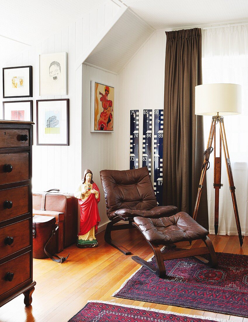 Sessel und Fussschemel mit braunem Lederbezug auf Orientteppich neben Vintage Stehleuchte in traditionellem Wohnraum