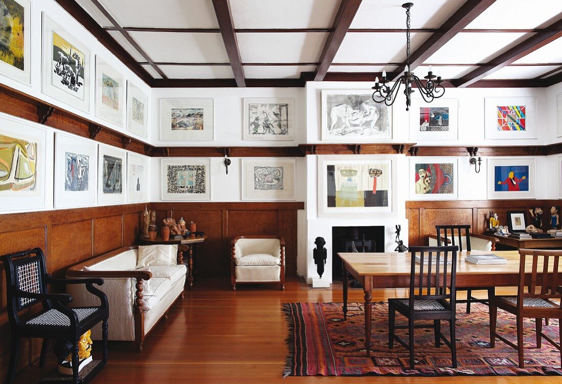 Wohnzimmer mit Essplatz gegenüber antike Sitzbank vor halbhoher Holzverkleidung und Bildergalerie