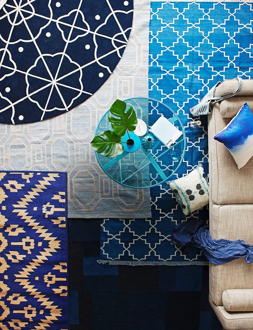 Rugs in shades of blue with various patterns in living room with glass table and sofa