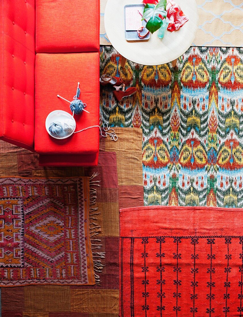 Bunte Teppiche in einem Wohnzimmer mit Couchtisch und rotem Sofa