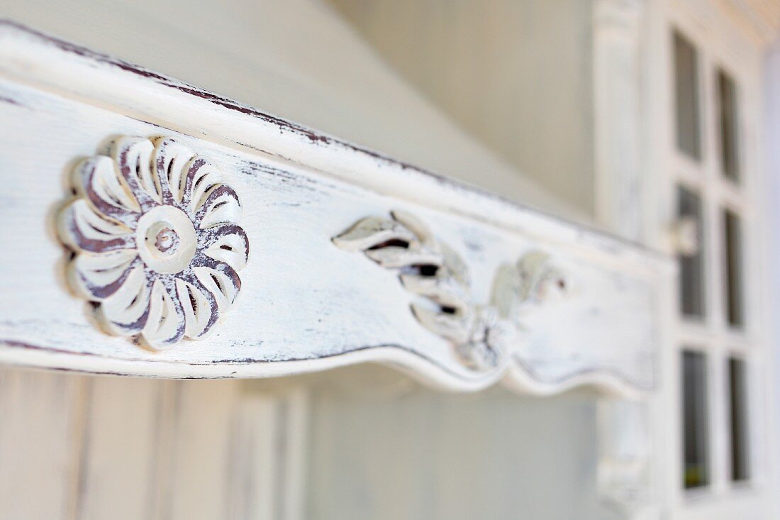 Detail of wooden extractor hood painted white and carved with rosettes