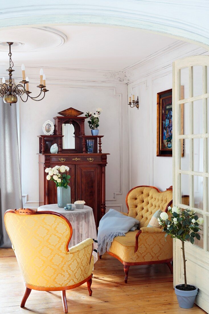 Blick durch offene Tür in Salon-Ecke mit Stilmöbel, goldgelber Seidenbezug mit Ornamentmuster auf Sessel und Sofa im Barock Stil