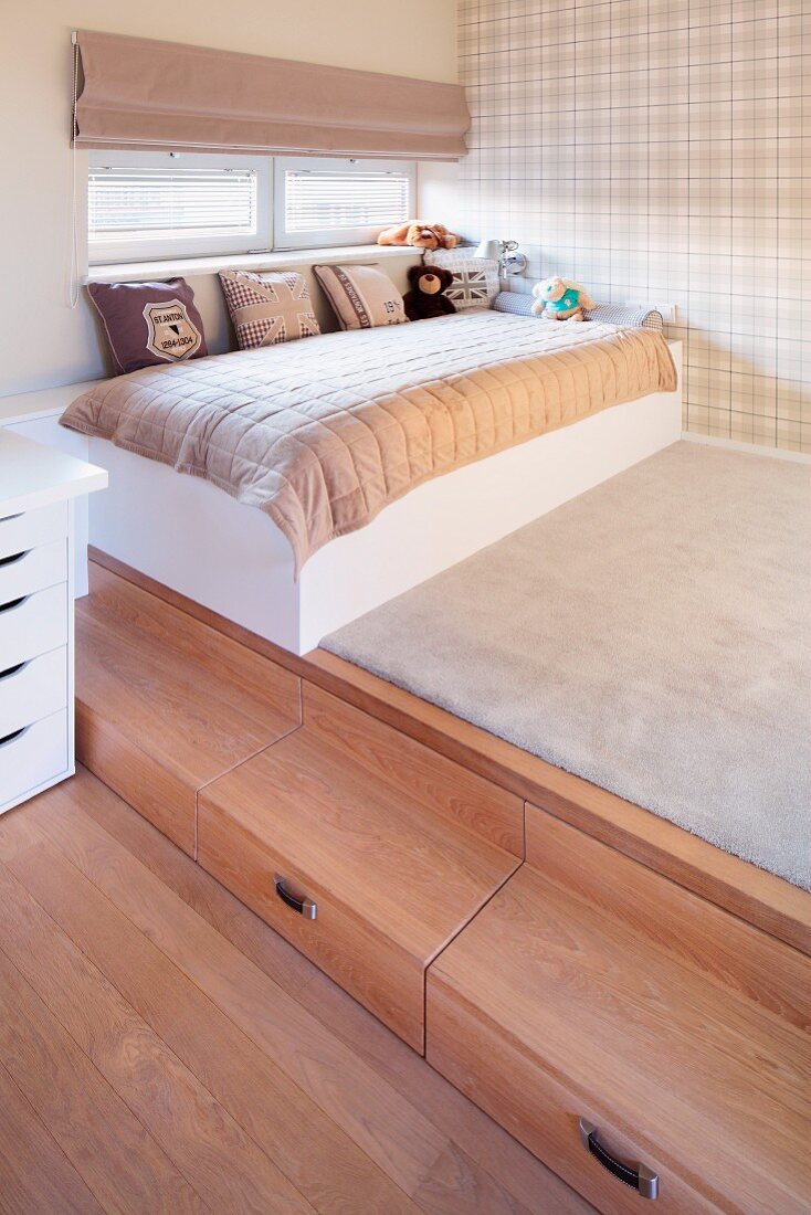 Platform with wooden steps, child's bed with scatter cushions and pale tartan wallpaper