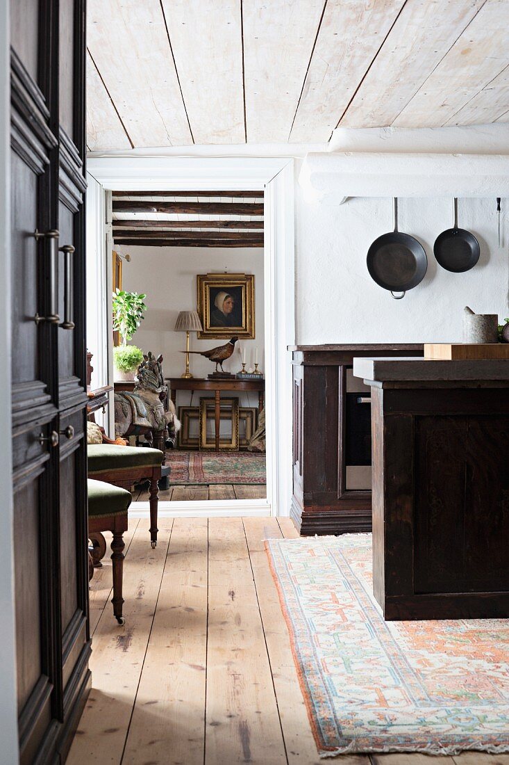 Free-standing dark-wood counter in kitchen with view into adjacent room through open door