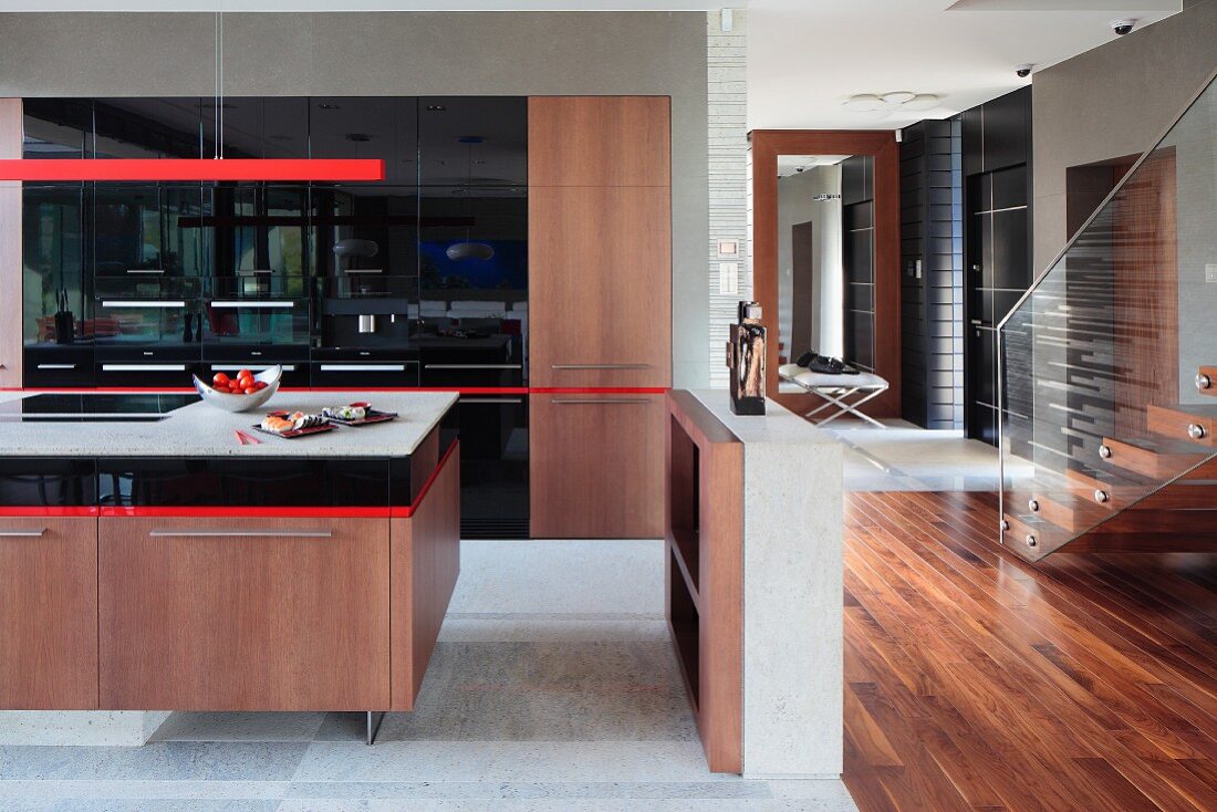Ausschnitt eines offenen Kochbereiches, Küchenblock mit Holzunterschrank, oberhalb rote, Stab Hängeleuchte in modernem Ambiente