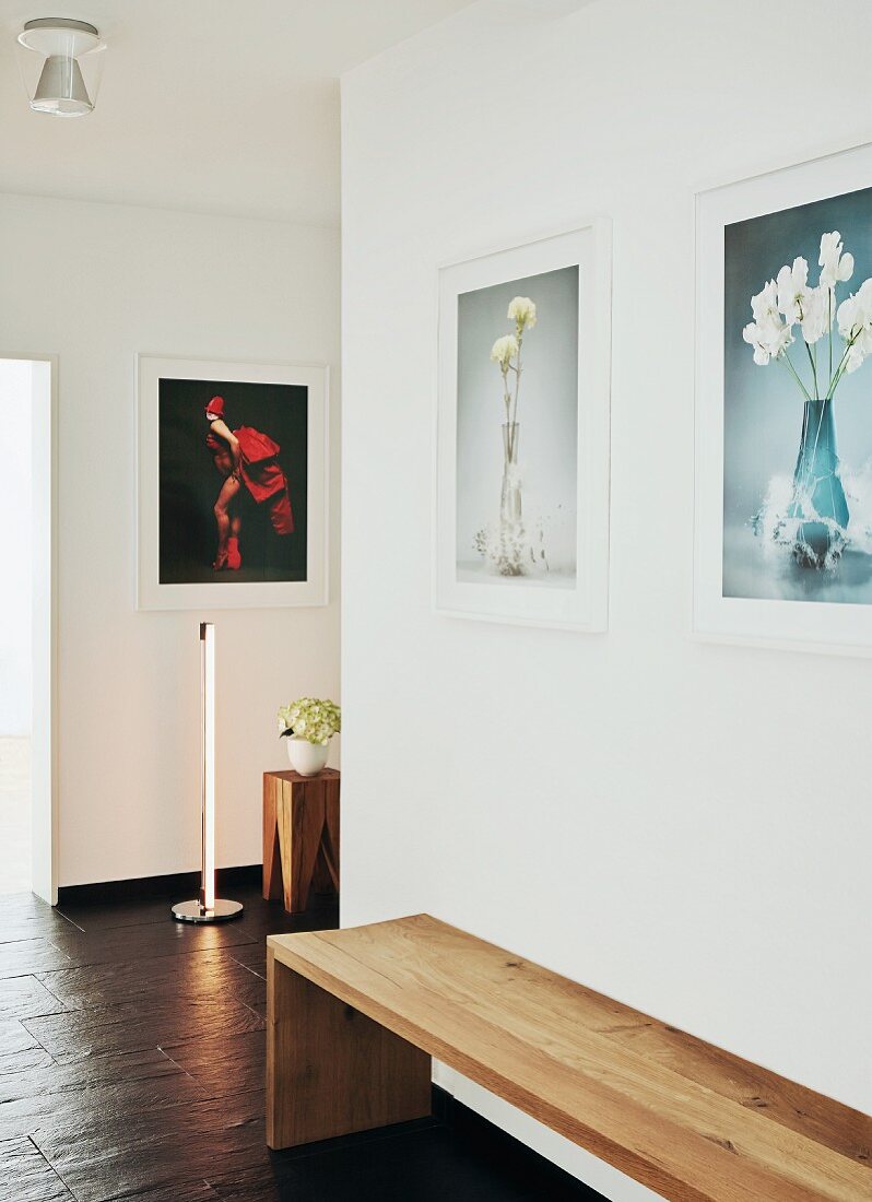 Minimalistische Holzbank auf schieferartigem Bodenbelag in zeitgenössischem Flur, an Wand Fotos mit Blumenmotiven