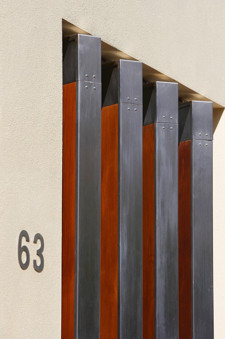 Ausschnitt einer Hausfassade mit drehbaren Fensterläden aus Holz im Metallrahmen