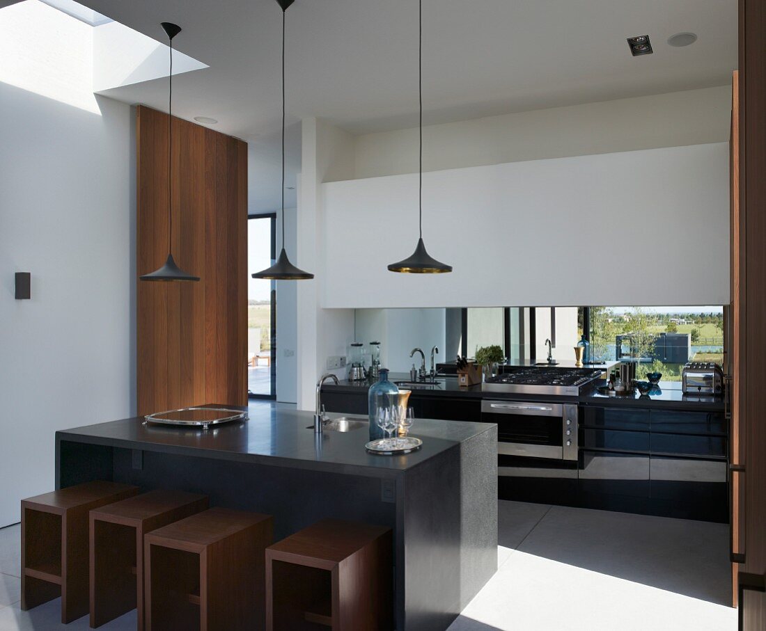 Kitchen unit with view of landscape and cubic dining furniture with wooden stools beneath sunny skylight in South American designer kitchen-dining room