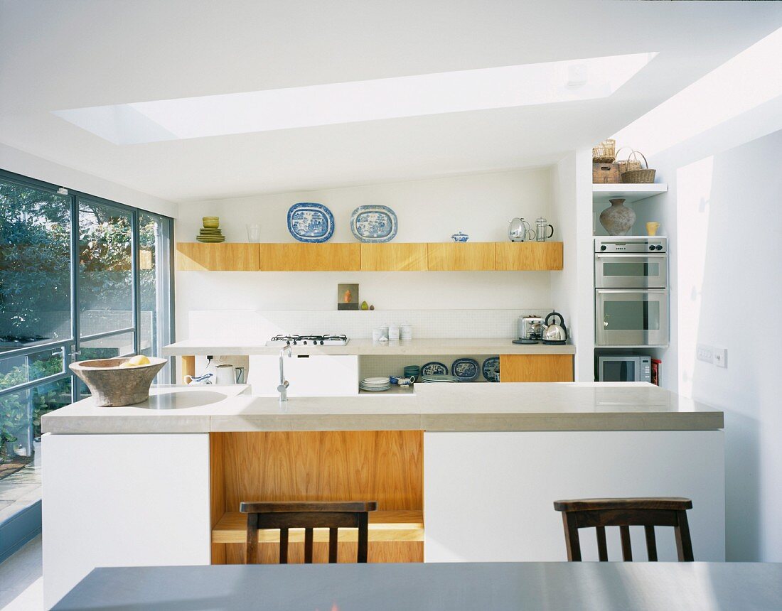 weiße Designerküche mit Küchenblock unter Oberlicht in zeitgenössischer Architektur