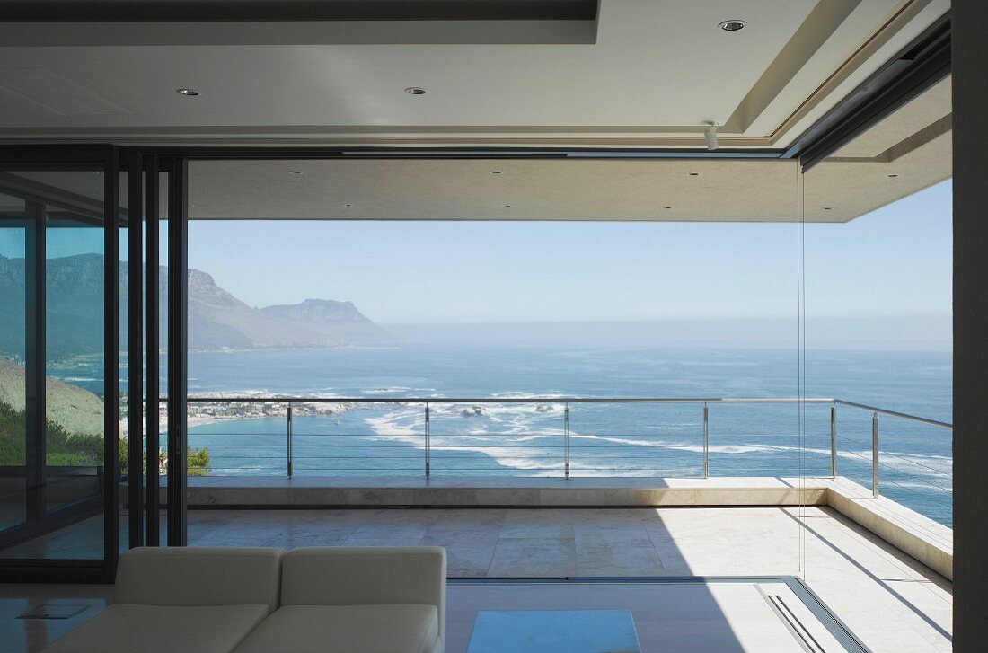 Zeitgenössisches Wohnhaus mit geöffneten Terrassentüren und eindrucksvollem Blick auf das Meer