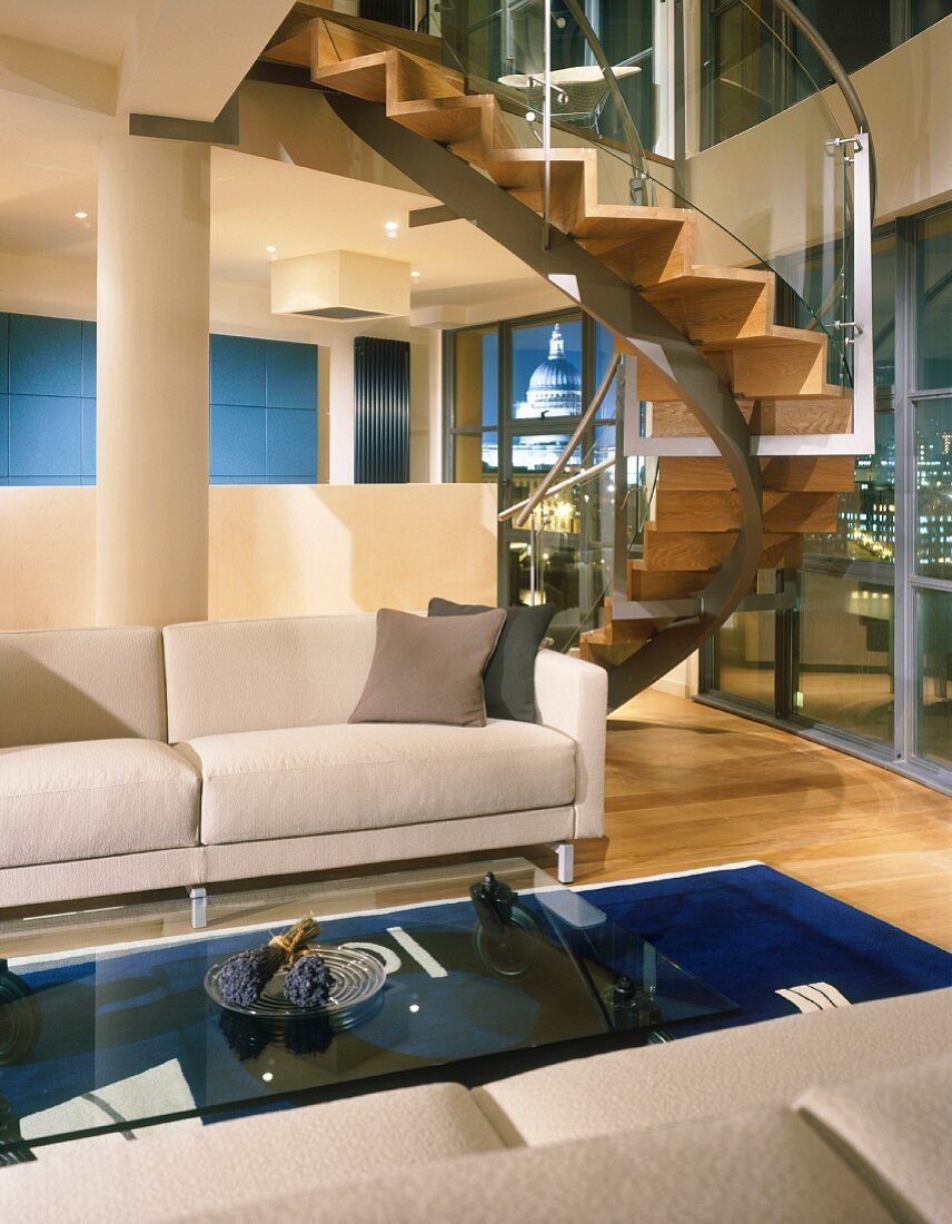 Curved staircase in a modern living room with white sectional sofa and glass coffee table