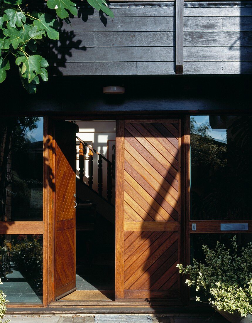 Eingangstür aus Holz mit offenstehendem Türflügel und Blick auf Treppe
