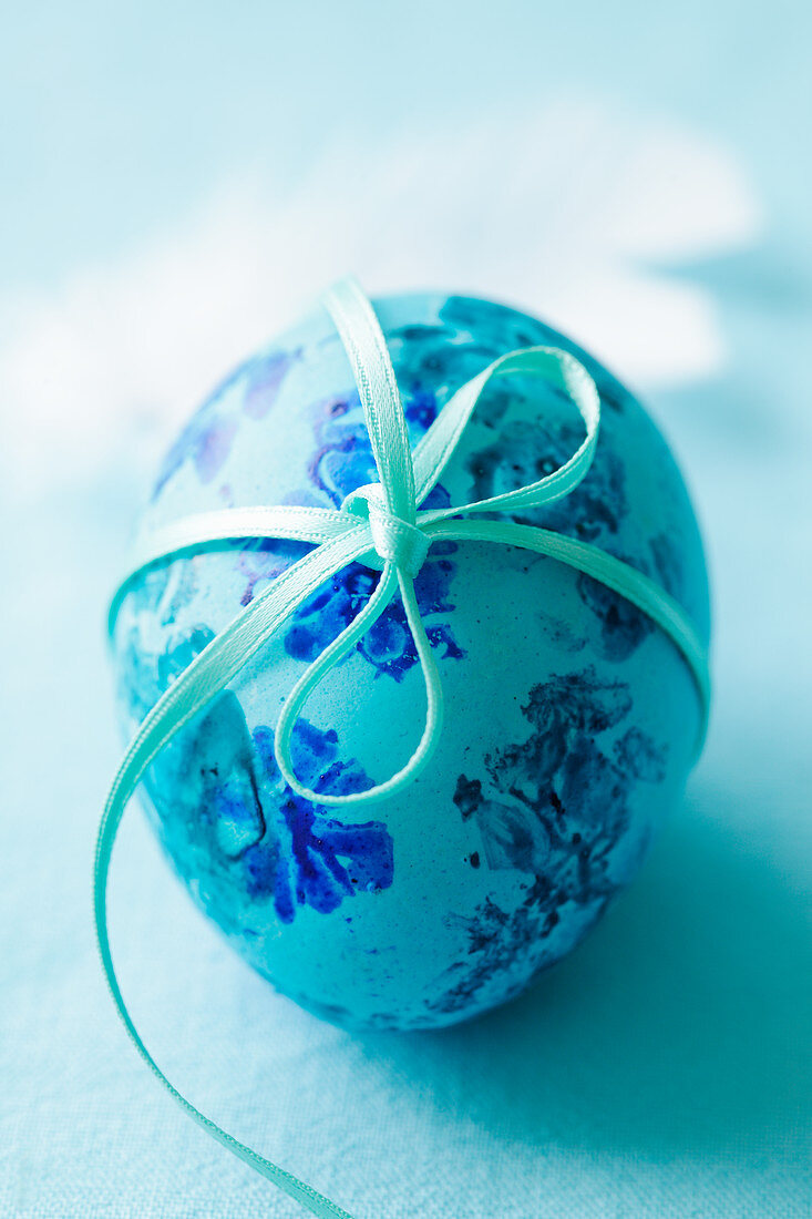 A turquoise Easter egg tied with ribbon