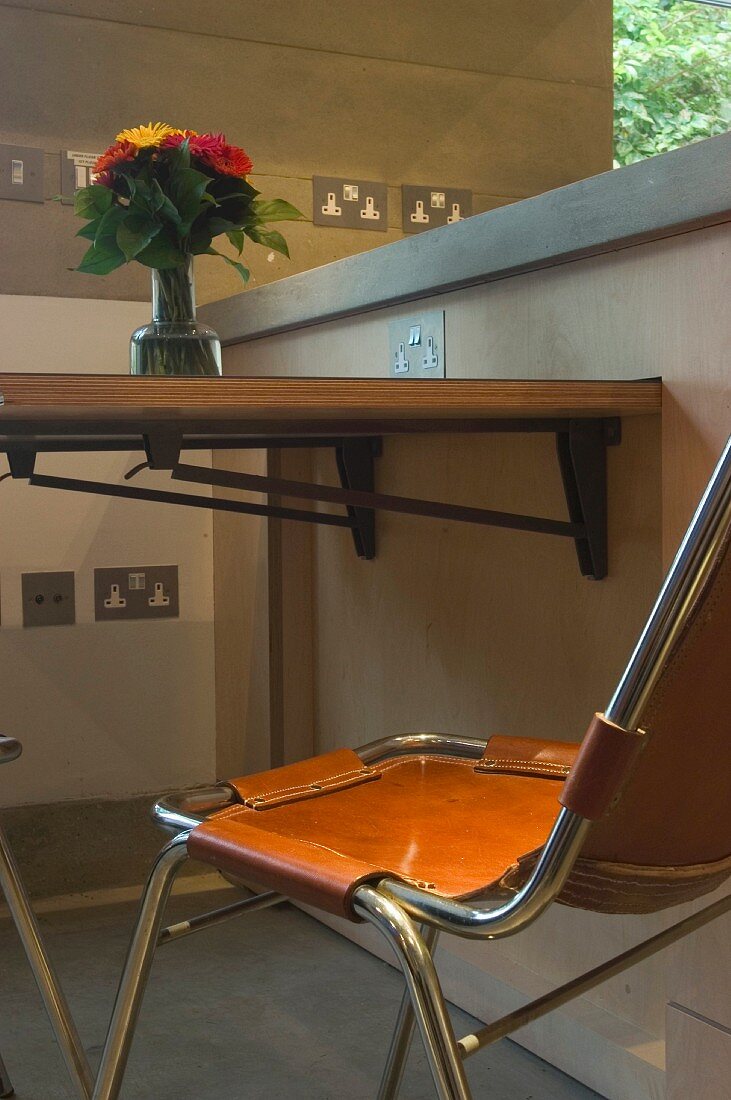 Klappbare Tischplatte an Wand und Stuhl mit Lederbezug im Retrostil
