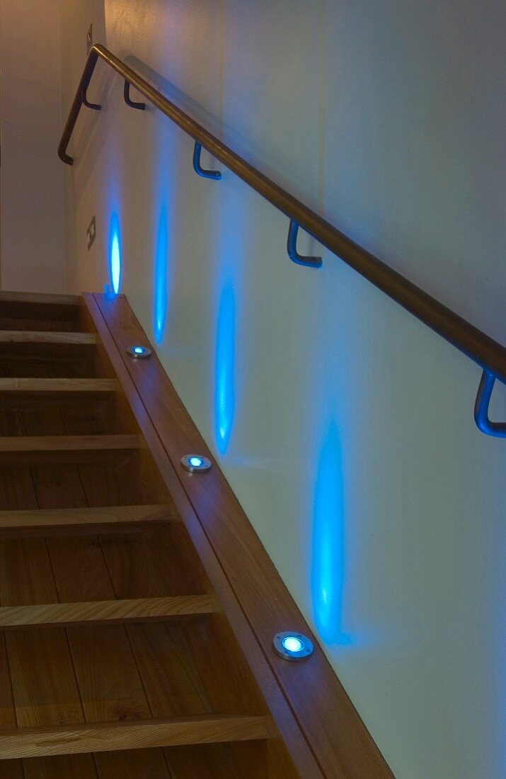 Treppenaufgang aus Holz mit eingebauten Bodenstrahlern in Wange und blau leuchtendem Licht