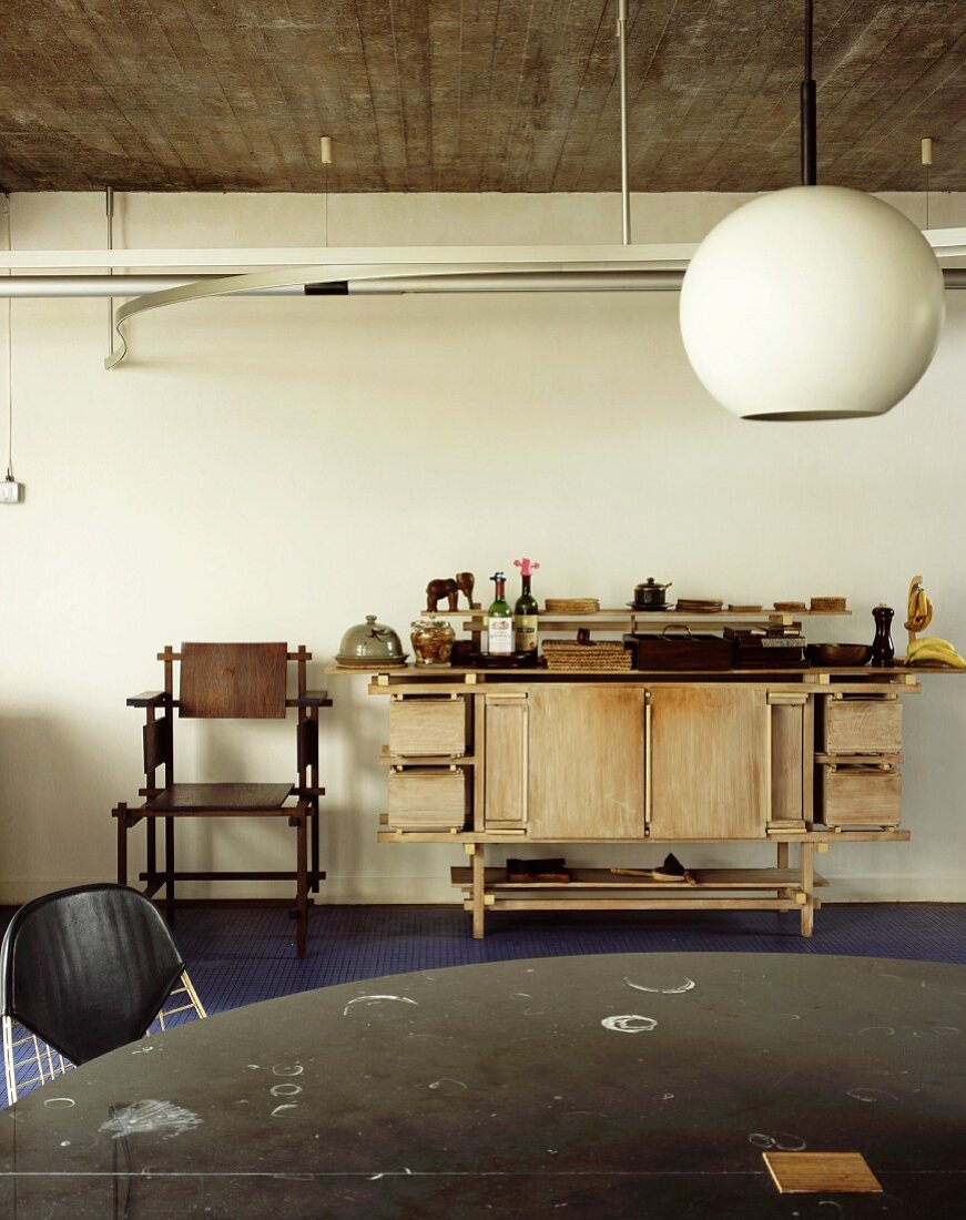 Kugelförmige Hängelampe im Retrostil und alte Werkbank aus Holz an Wand