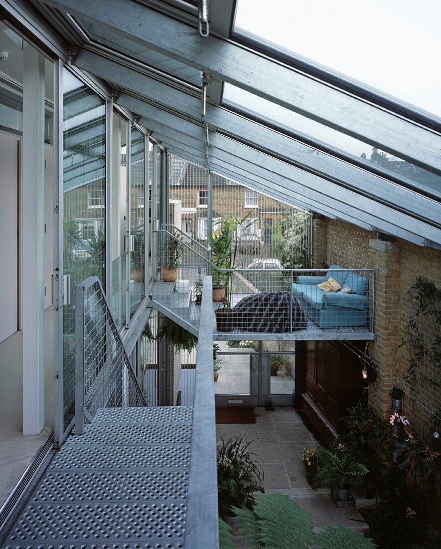 Überdachter Innenhof mit Glasdach und Treppenzugängen aus Metall und Gitterrosten
